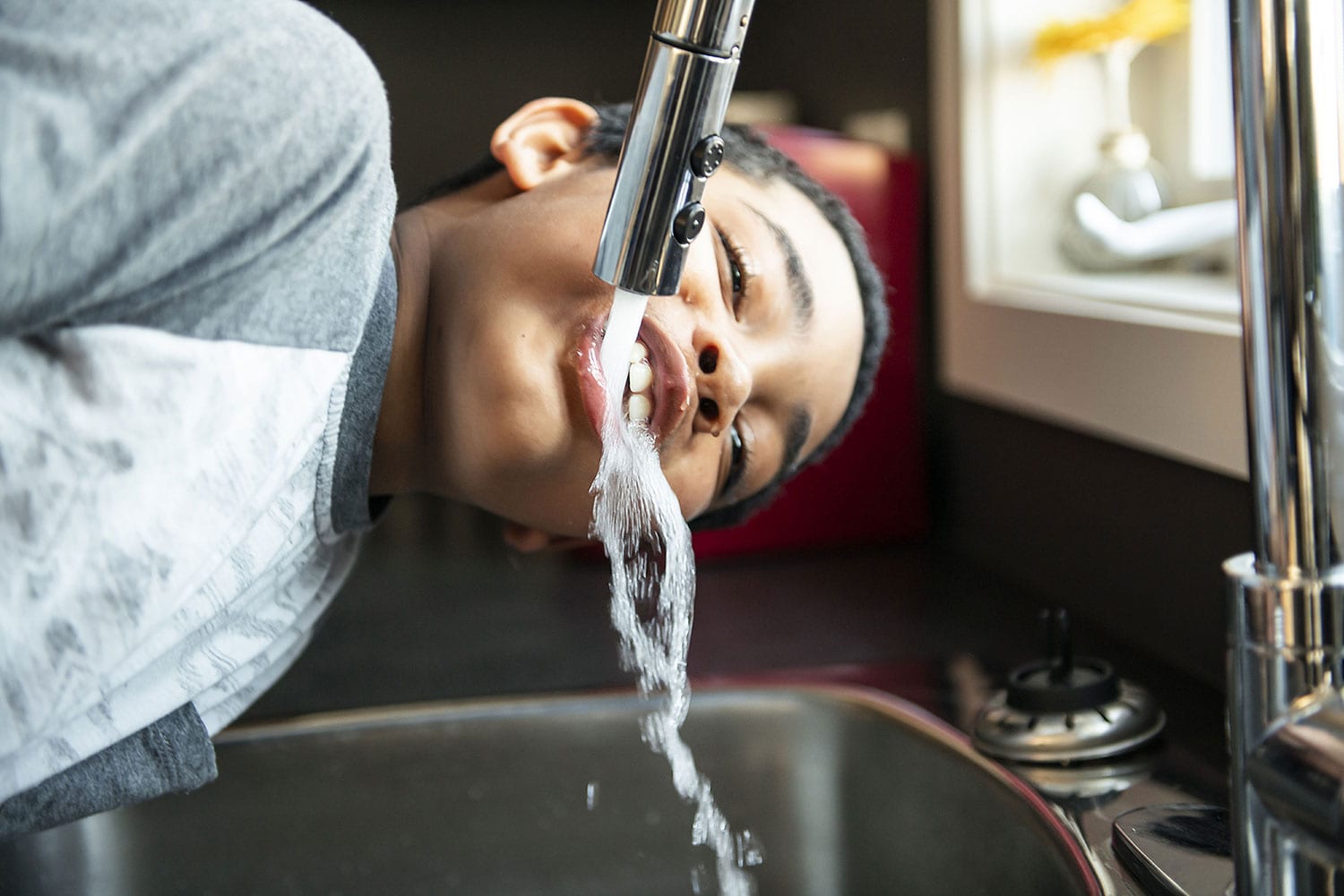boy drinking water from the faucet